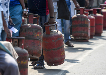 People wait with their empty domestic gas cylinders outside a delivery centre to collect refilled cylinders during a government-imposed nationwide lockdown as a preventive measure against the COVID-19 coronavirus, in Howrah on the outskirts of Kolkata on March 28, 2020. (Photo by Dibyangshu SARKAR / AFP)
